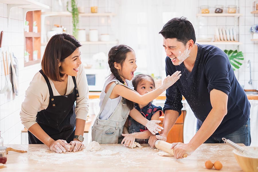 Personal Insurance - Family Rolls Out Cookie Dough, Kids Covering Their Parents With Flour, in Their Bright White Kitchen